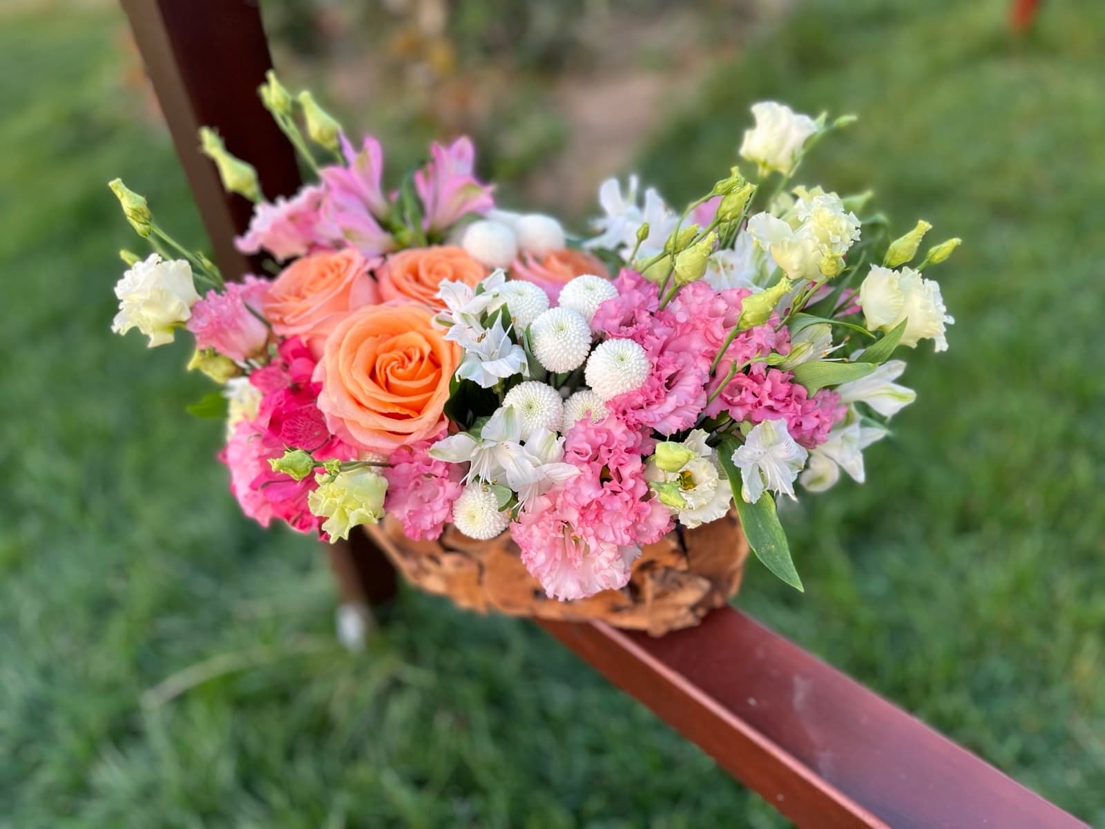 A colorful floral arrangement on a wooden log in an orchard at golden hour